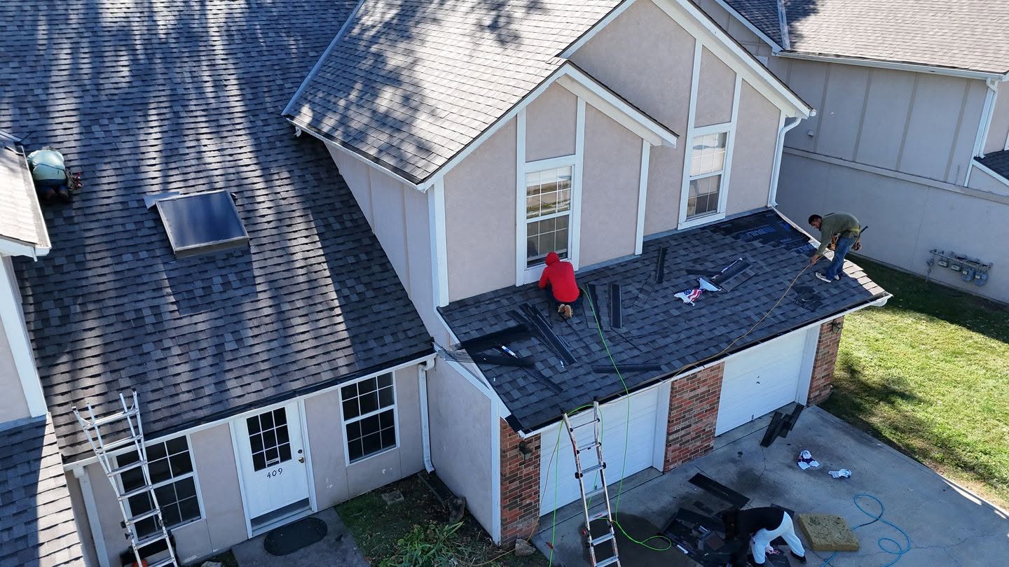 Brown Roofing crew reshingling asphalt roof, full roof replacement in progress.